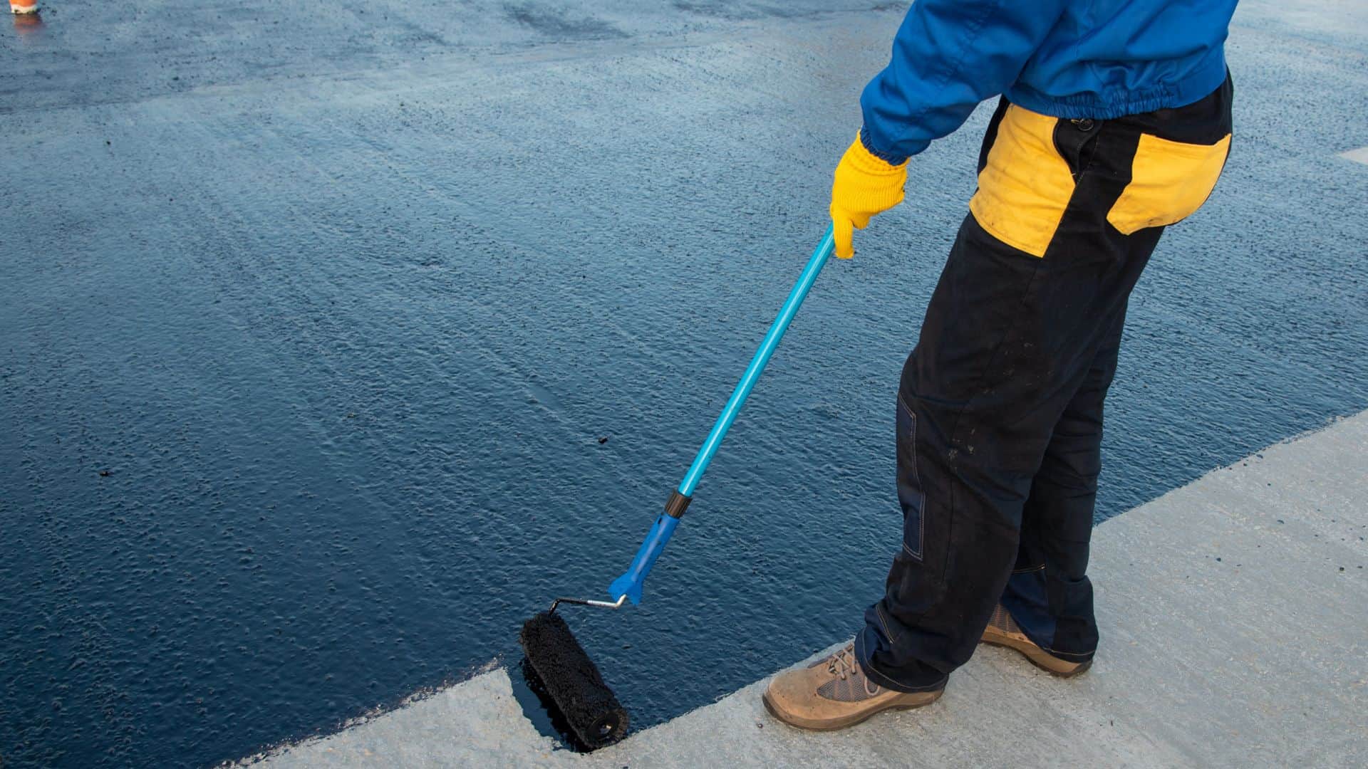 Person waterproofing ground with roller and product